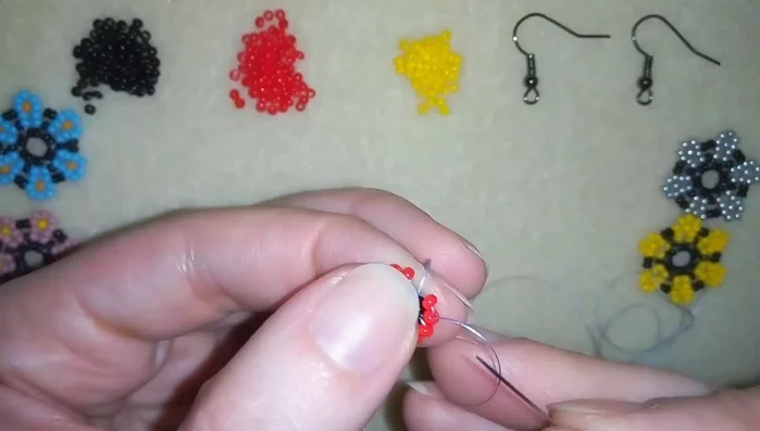 Continue adding the red-yellow-red bead sequence, interspersed with single black beads, to form the flower petals.