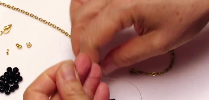 Assemble focal bead section: String the end link of the oxidized black chain, three 6mm black rondelle beads, the end link of the 4.5-inch gold chain, and then alternate 14 small black beads with 13 larger 8mm beads. Finish with the end link of the gold chain, three more 6mm black rondelles, and the end link of the oxidized chain.