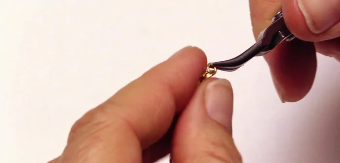 Attach to chain: Use the open links of the chain as jump rings to attach the crimped end to a chain.