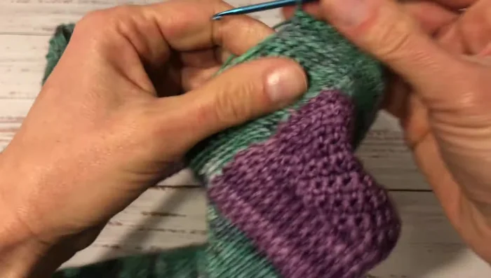 Make a round of decreases (two single crochets together, then two single crochets) to reduce width.
