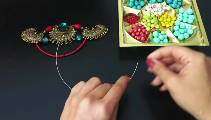 Attach the bottom portion: Attach the completed beaded wire rows to the metal components of the necklace.