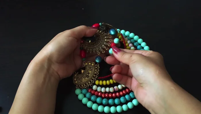 Decorate the center: String seven large beads onto a pin with a ball at the end. Secure this to the center of the necklace.