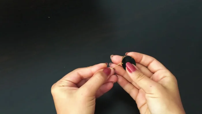 Create the central pendant piece: Attach a gilded pin with a loop to a metal piece. String coral beads, a large oval crystal, and another bead onto the pin. Secure the pin to the central metal part.