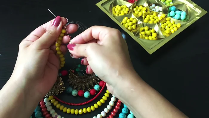 Secure the center decoration: Use another pin with a loop to pass through the center beads twice, tightening the line and making knots to secure the beads.