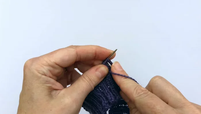 Creating the lace stitch: Knit two stitches together, yarn over (anti-clockwise), knit the next two stitches, and purl.