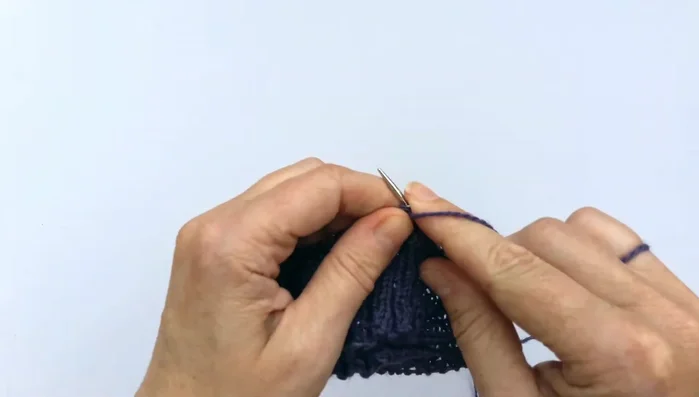 Completing round one: Repeat the purl, knit two together, yarn over, knit two, purl sequence until the end of the round.