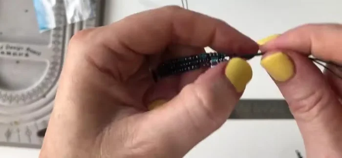 Tie a knot at the loose ends of the threads to create a secure finish.