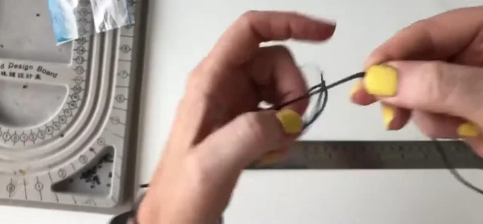 Tie a knot at the loose ends of the threads to create a secure finish.