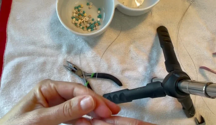Create the first end loop. Squeeze the end of the wire to create a small loop, slide on a crimp tube, and crimp it tightly using flat nose pliers.