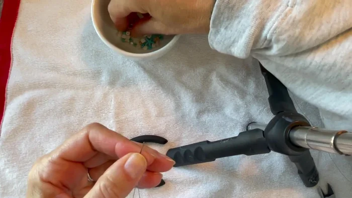 Add an initial bead to both strands. Thread one bead onto both wires and slide it down to the bottom.