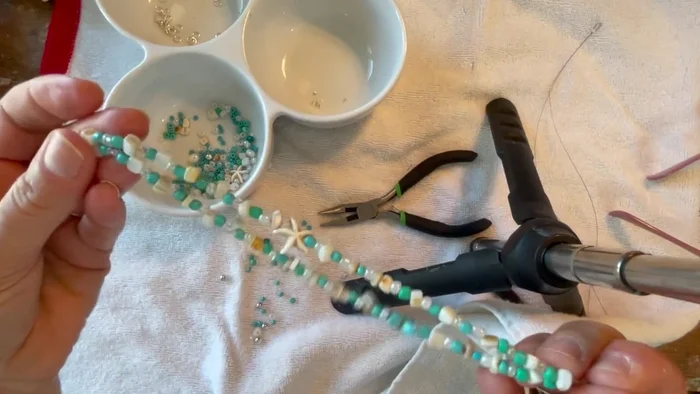 Create the second end loop. Bring the two wires together, add a bead to hold them, and crimp the end using a crimp tube and flat nose pliers.