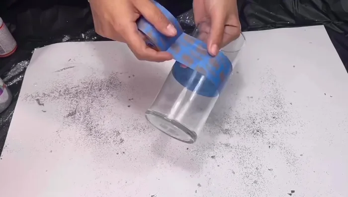 Tape the bottom half of the cylinder vase and spray paint it black. Let it dry.