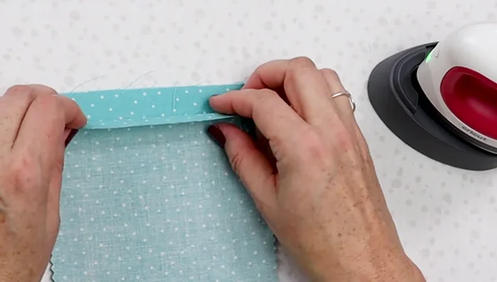 Fold down about a quarter inch from the top edge, press. Fold down one more time, press, to encapsulate raw edges. Zigzag stitch along the folded edge.