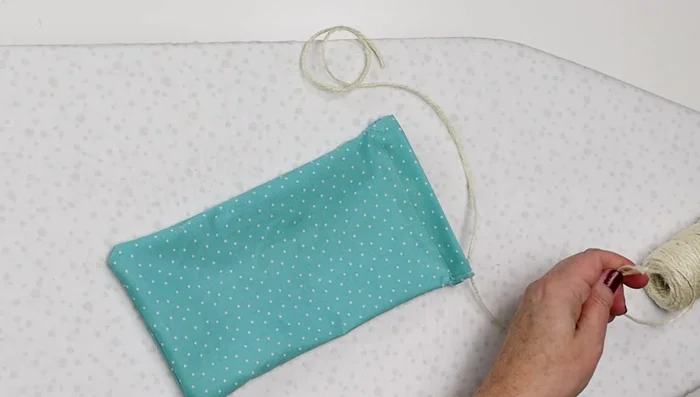 Cut two pieces of string (or twine) approximately four times the width of the bag. Use safety pins to thread the strings through the channels. Tie off and trim excess string.