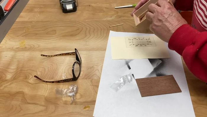 Adhere the printed clock face to a piece of plywood using spray contact adhesive. Trim excess paper.