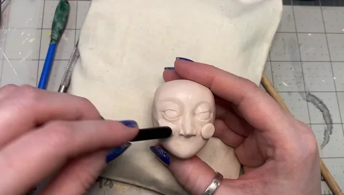 Add clay to cheeks, continuously blending and refining.