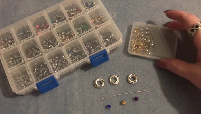 Gather materials: adjustable bracelet components, sew-on rhinestones (various birthstone colors), eye pins, round beads, pliers, and E6000 glue (optional).