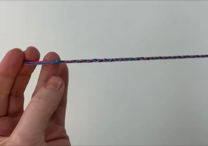 Prepare your friendship bracelet. It should be about 16 centimeters long, braided in the middle with a knot at each end and approximately 10 centimeters of loose threads on either side.