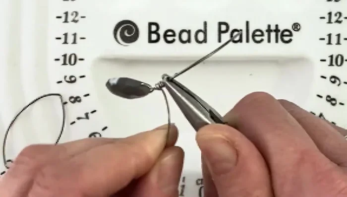 Wrap the remaining wire tightly around the base of the bead, continuing until you achieve a neat, covered look.