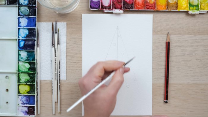 Sketch a simple triangle for the Christmas tree and mark small circles where the lights will go.