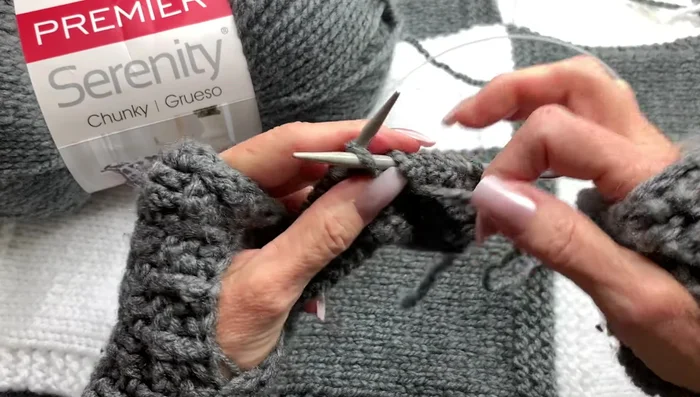 Continue alternating knit and purl rows (knit three, purl nineteen, knit three) for 13 rows to create a stockinette stitch panel with garter stitch borders.