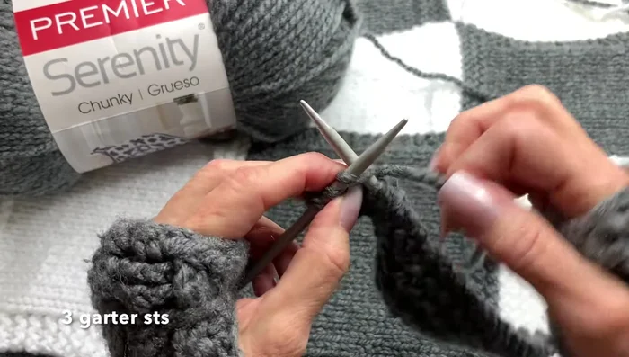 Continue alternating knit and purl rows (knit three, purl nineteen, knit three) for 13 rows to create a stockinette stitch panel with garter stitch borders.