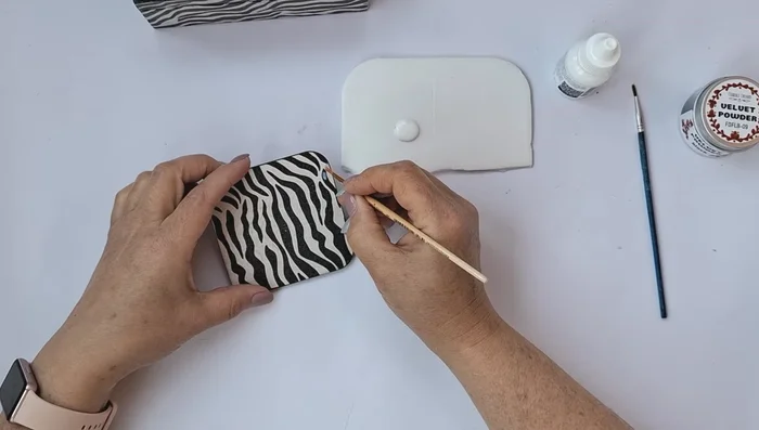 Apply sticky glue to the black stripes on the sides of the box and sprinkle with flock. Remove excess flock with a stiff brush.