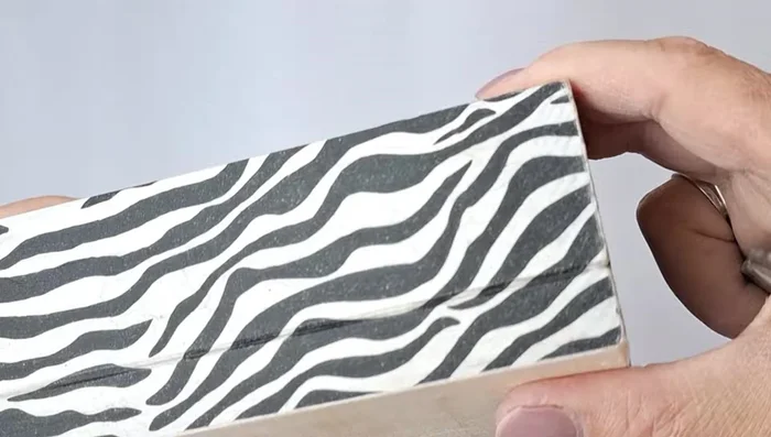 Carefully cut the napkin along the border of the upper and lower parts of the box using a clerical knife.