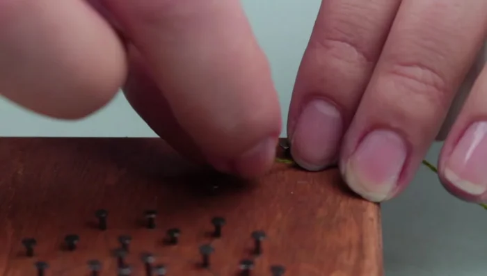 Weave green thread around the nails to create the dandelion stem.