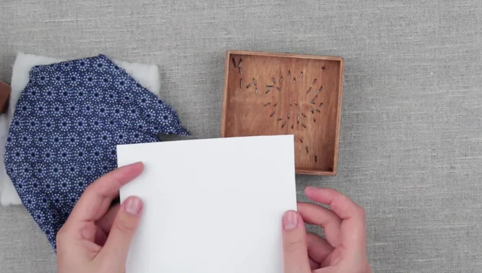 Attach the fabric-covered cardboard to the inside of the lid with tape to create a soft interior.