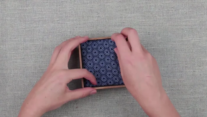 Attach the fabric-covered cardboard to the inside of the lid with tape to create a soft interior.