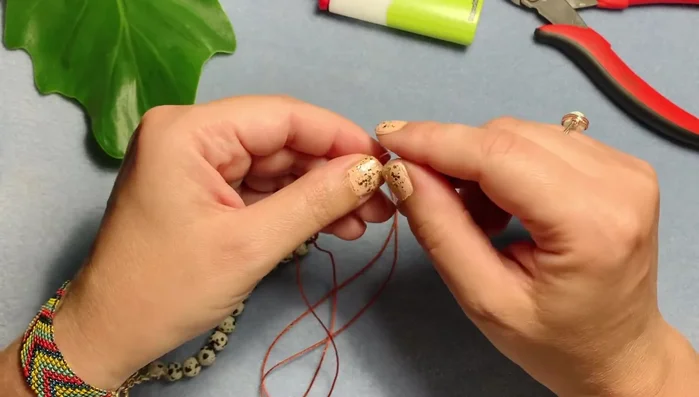 Add a sandalwood bead (or any bead of your choice) and tie another overhand knot, pulling it tight against the bead.