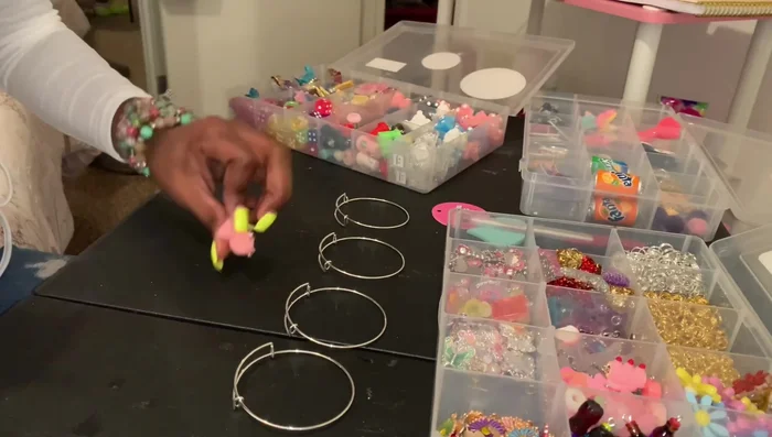 Select charms based on color coordination and personal preference. The creator uses mostly pink charms with a few others to add variety.