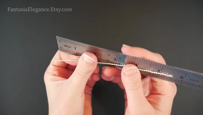 Shape the center piece: Bend the twisted wire in half again at the 2.75-inch mark to create a V-shape. Gently shape the wire into a wave-like form, curling the ends into open spirals using round nose pliers.