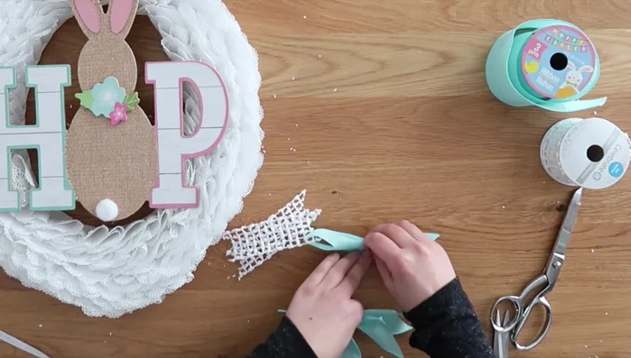 Glue the bow onto the wreath, covering the sign's attachment point.
