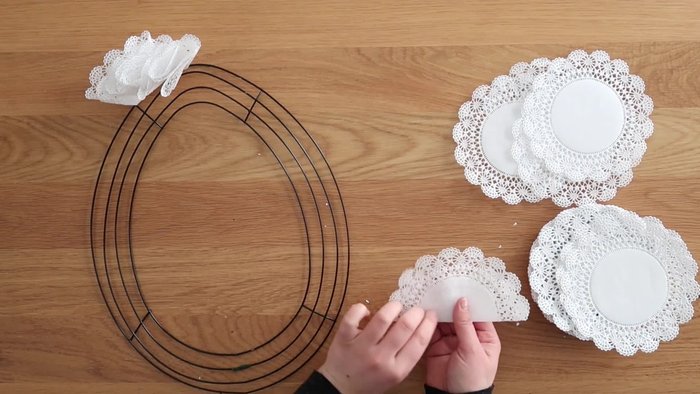 Fold each paper doily in half, slightly offsetting the middle seam to create dimension. Then, fold it into thirds, forming a cone shape.