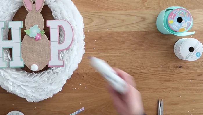 Glue the bow onto the wreath, covering the sign's attachment point.
