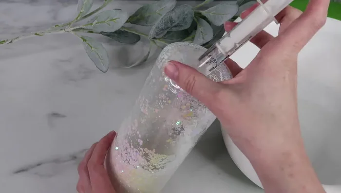 Gently manipulate any remaining air bubbles to the opening and carefully add more liquid mixture to fill the space. If a large bubble persists, consider using a syringe with a fine tip.