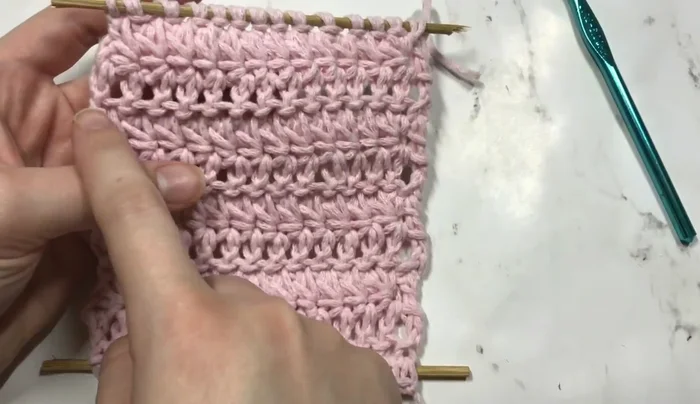 Add fringe to the bottom of the wall hanging by threading yarn pieces through the spaces between the double crochets.