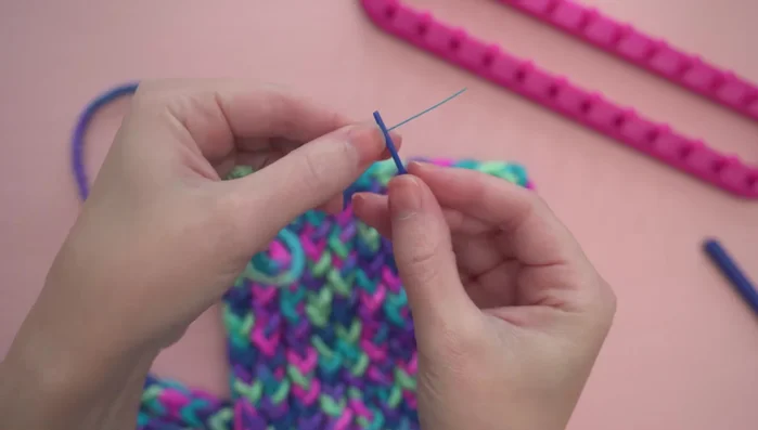 Optional: Adding a twist by attaching a length of yarn to a corner, folding it in half, and sewing through all four layers.