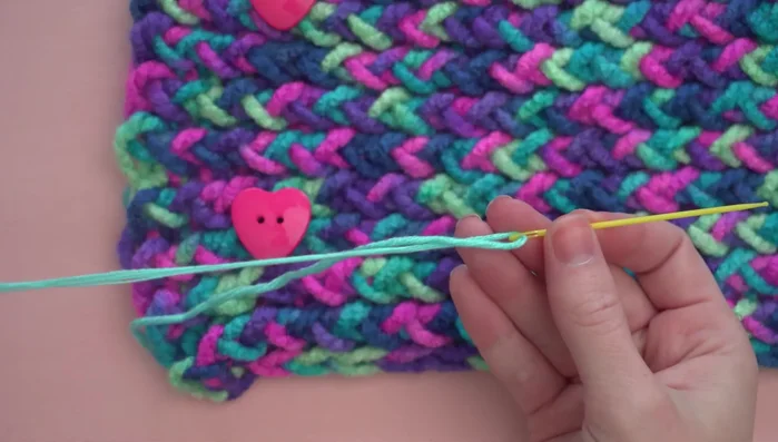 Optional: Adding a twist by attaching a length of yarn to a corner, folding it in half, and sewing through all four layers.