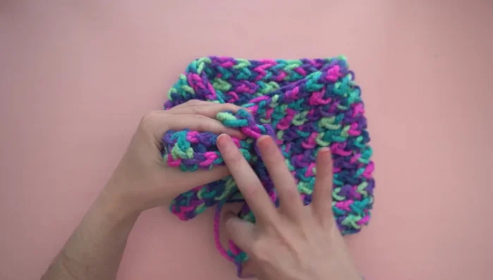 Optional: Adding a twist by attaching a length of yarn to a corner, folding it in half, and sewing through all four layers.