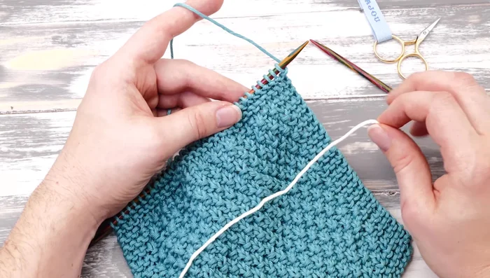 Cut off the first color yarn and tie a simple knot to secure the stitches. Bind off all stitches using the standard bind-off method.