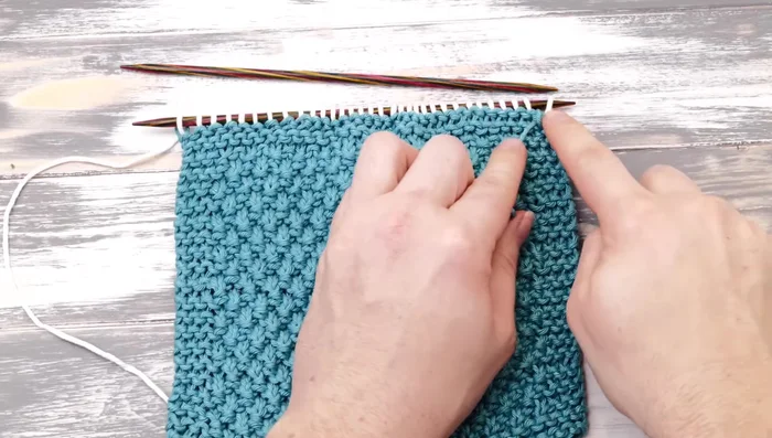 Cut off the first color yarn and tie a simple knot to secure the stitches. Bind off all stitches using the standard bind-off method.