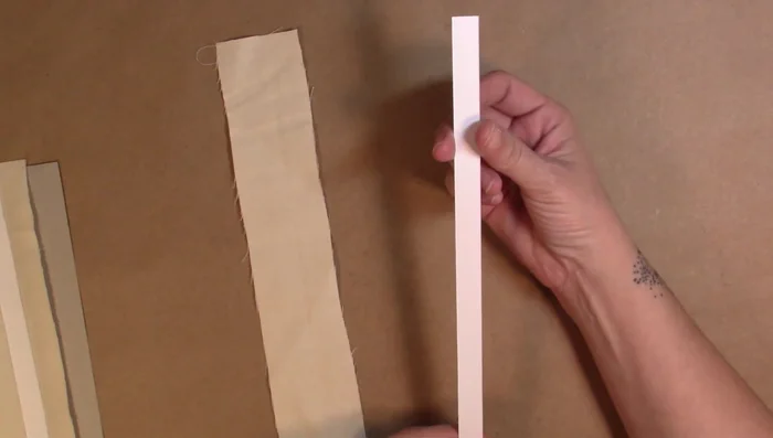 Prepare the gusset piece (paper) and fabric canvas. Glue the gusset into the center of the fabric, leaving an overhang.