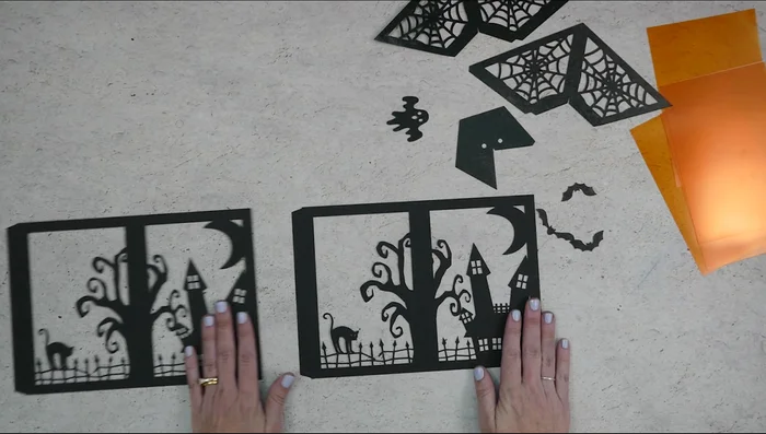 Assemble the lantern: Glue the transparency panels inside the bottom pieces, then glue the bats and ghosts. Fold along perforation lines and glue the two bottom pieces together.