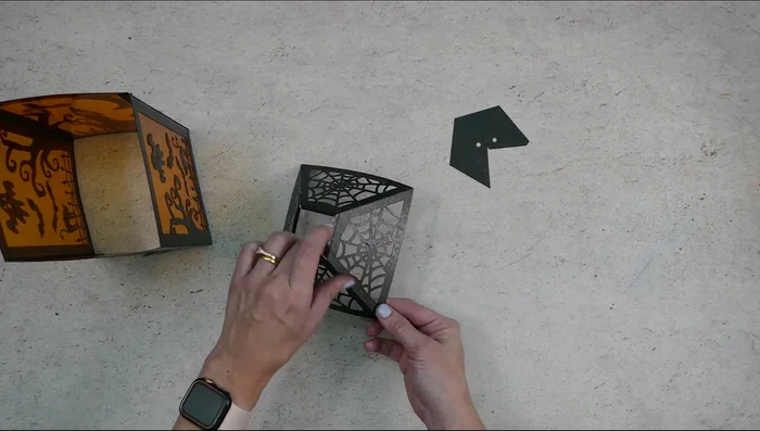 Glue the spider web section onto the lantern base, followed by the long rectangle piece and top triangle piece.