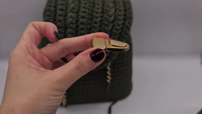 Attach the lock by squeezing the upper part open and poking the lower part through the backpack, bending it around the spikes.