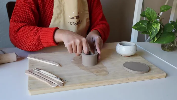 Score both ends of the cylinder, apply water, and attach the ends to form a complete cylinder. Use a tool to blend the seam.