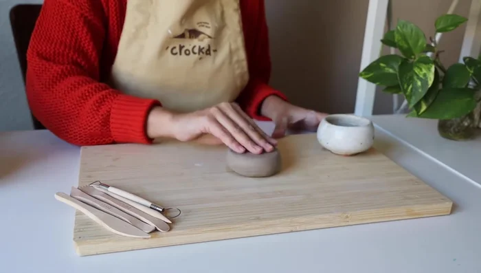 Flatten the clay ball into a smooth slab, about a quarter of an inch thick (3/4 cm). You can use a rolling pin, glass jar, or your hands.